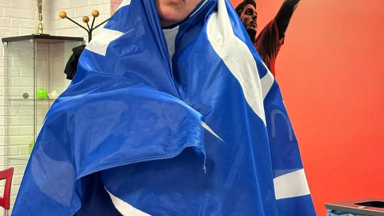 Een begeleidster met een CSV-vlag om haar hoofd en schouders geslagen.