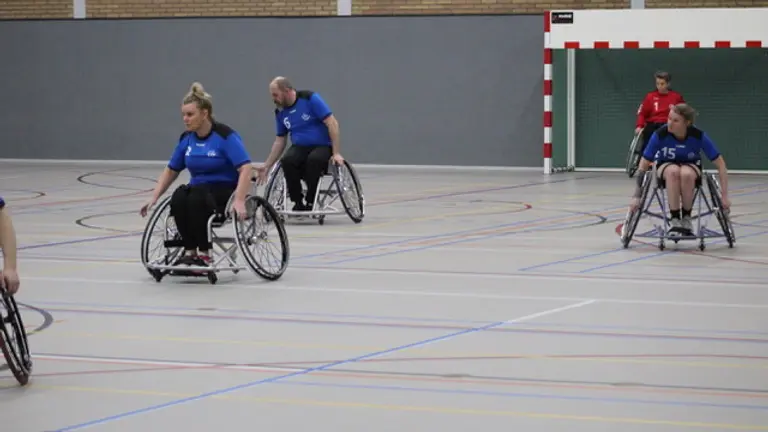 Rolstoelhandbalsters van CSV-2 in blauw in actie op het veld tijdens de derby.